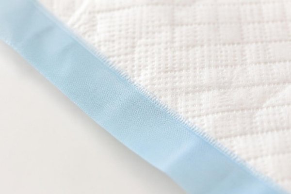 Macro of the sealed edge where the quilted top sheet meets the blue waterproof backing